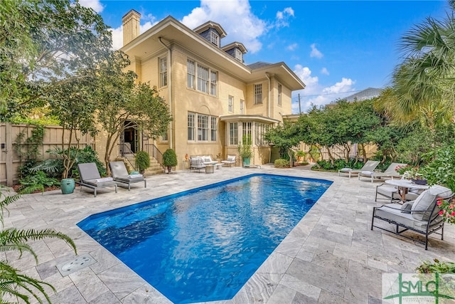 back of house featuring a fenced in pool, a chimney, a patio area, and a fenced backyard