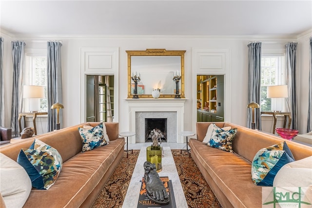 living room featuring crown molding, plenty of natural light, and a fireplace with flush hearth