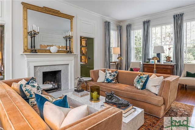 living room featuring crown molding, a premium fireplace, and wood finished floors