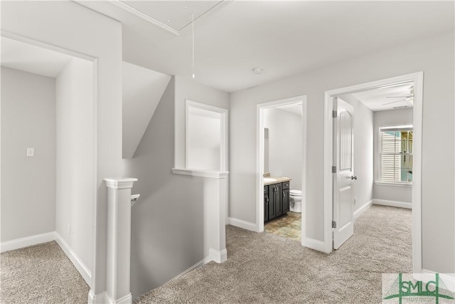 hallway featuring light carpet, attic access, baseboards, and an upstairs landing