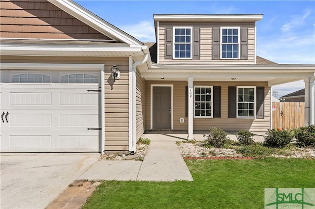 view of front of property featuring an attached garage, covered porch, fence, and a front lawn