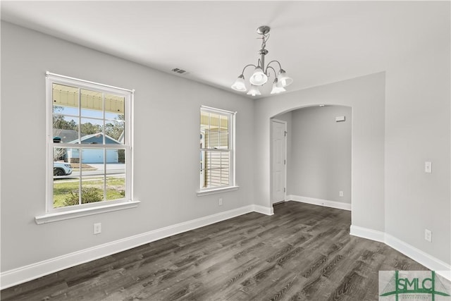 spare room featuring arched walkways, a notable chandelier, visible vents, dark wood-type flooring, and baseboards