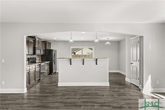 kitchen with a kitchen breakfast bar, stainless steel appliances, dark brown cabinets, light countertops, and pendant lighting