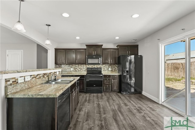 kitchen featuring hanging light fixtures, light countertops, dark brown cabinets, black appliances, and a sink