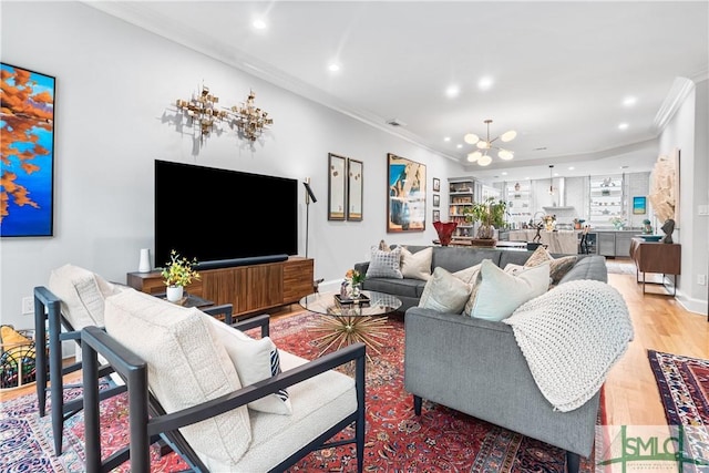 living room with a notable chandelier, recessed lighting, light wood-type flooring, and crown molding