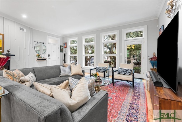 living area with visible vents, crown molding, and wood finished floors