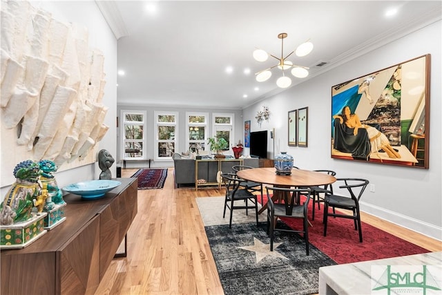 dining space featuring light wood-style flooring, a notable chandelier, visible vents, baseboards, and crown molding