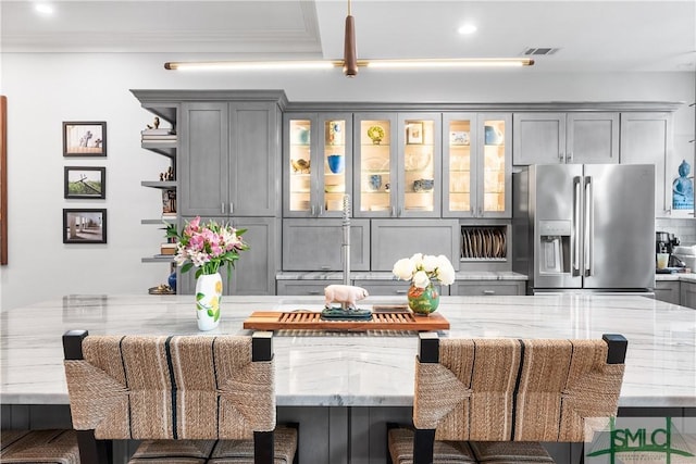 interior space featuring light stone countertops, visible vents, stainless steel refrigerator with ice dispenser, and gray cabinetry