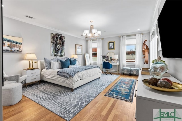 bedroom featuring a notable chandelier, crown molding, visible vents, and wood finished floors