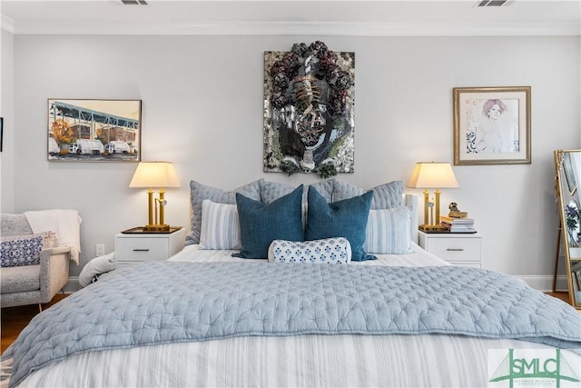 bedroom with baseboards, visible vents, ornamental molding, and wood finished floors