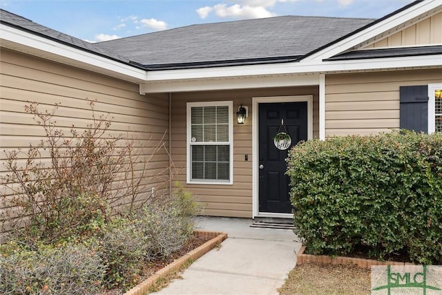 view of exterior entry with roof with shingles