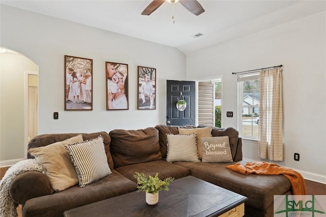 living area featuring arched walkways, lofted ceiling, a ceiling fan, wood finished floors, and baseboards