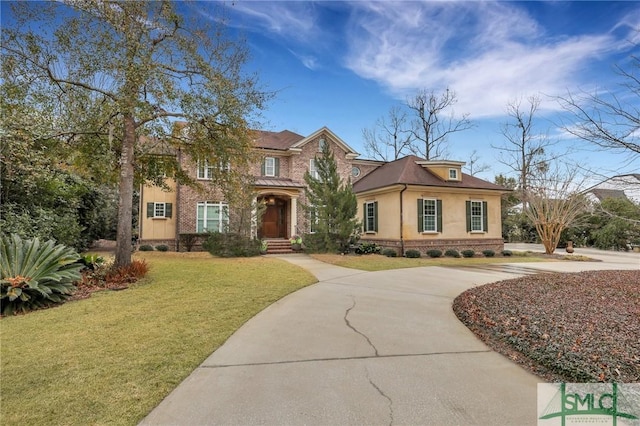 view of front of property with driveway, a front lawn, brick siding, and stucco siding