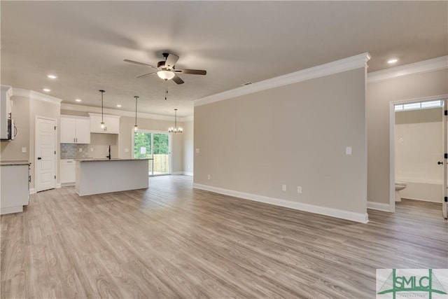 unfurnished living room with light wood finished floors, baseboards, ornamental molding, and ceiling fan with notable chandelier