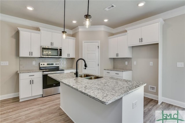 kitchen featuring stainless steel appliances, a sink, visible vents, white cabinets, and a center island with sink