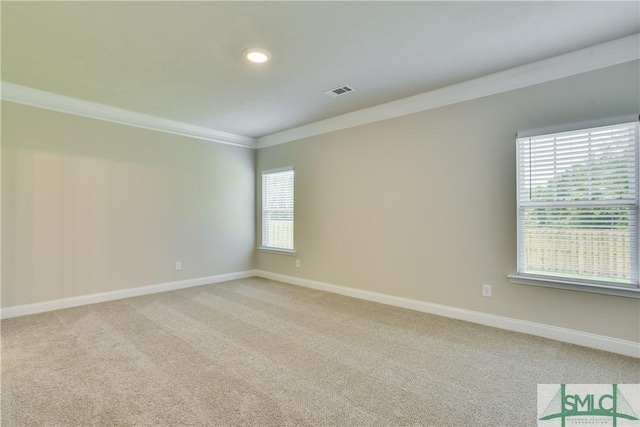 spare room featuring light carpet, ornamental molding, visible vents, and baseboards