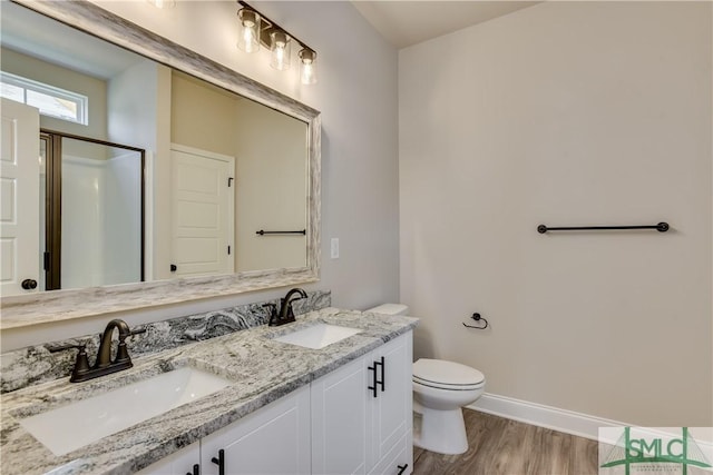 bathroom with toilet, baseboards, a sink, and wood finished floors