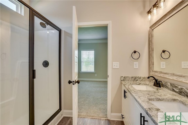 bathroom with double vanity, a stall shower, a sink, and crown molding