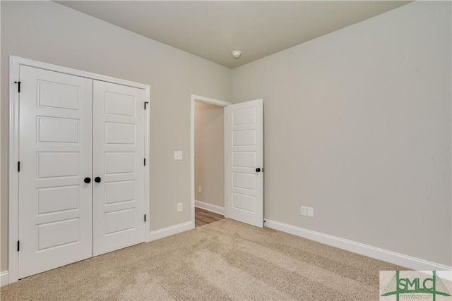 unfurnished bedroom with carpet, a closet, and baseboards