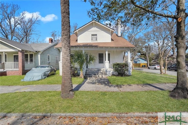 bungalow with covered porch, a front lawn, and a chimney