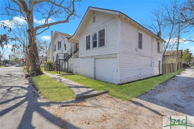 view of side of home featuring stairs and a yard