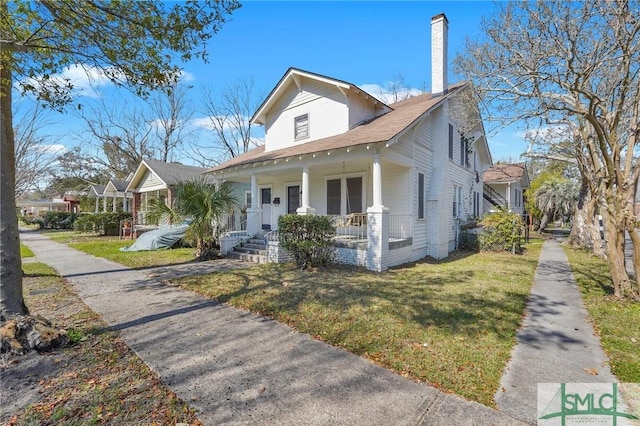 bungalow-style home featuring a front yard, covered porch, and a chimney