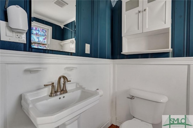 half bathroom with toilet, visible vents, and a sink