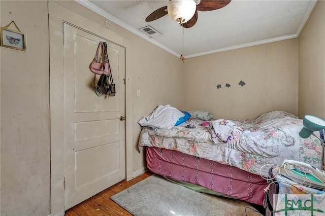 bedroom featuring crown molding, visible vents, ceiling fan, and wood finished floors