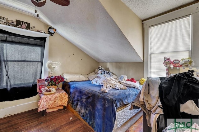 bedroom with vaulted ceiling, a textured ceiling, and wood finished floors