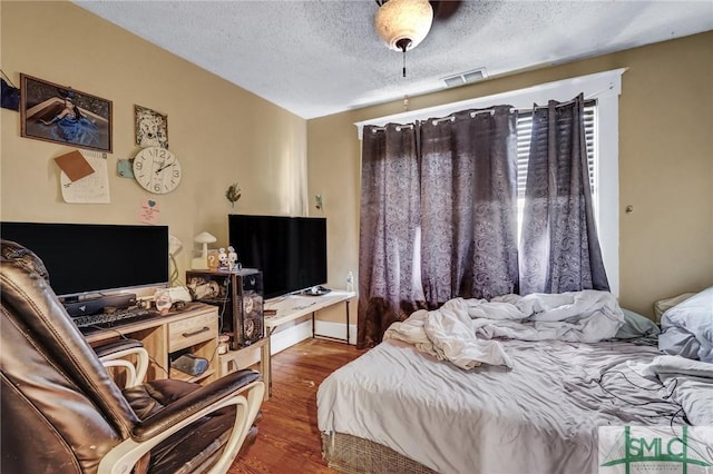 bedroom featuring a textured ceiling, wood finished floors, and visible vents