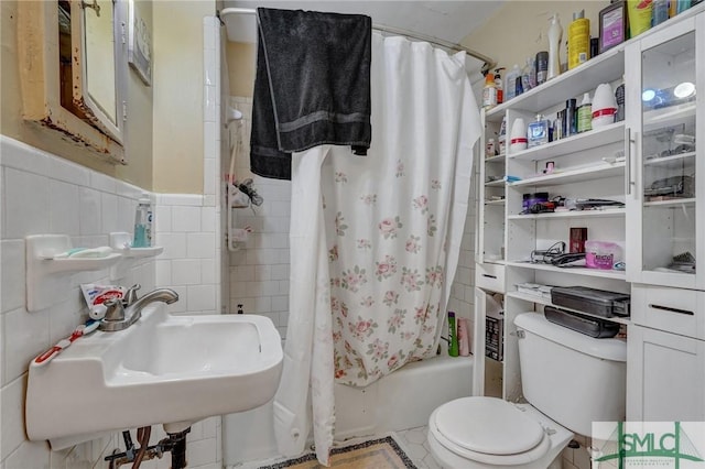 full bathroom featuring shower / tub combo with curtain, tile walls, toilet, wainscoting, and a sink