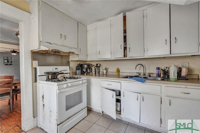 kitchen with a textured ceiling, white range with gas stovetop, light countertops, and a sink