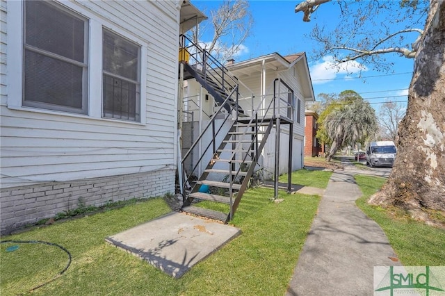 view of side of home featuring stairs and a lawn