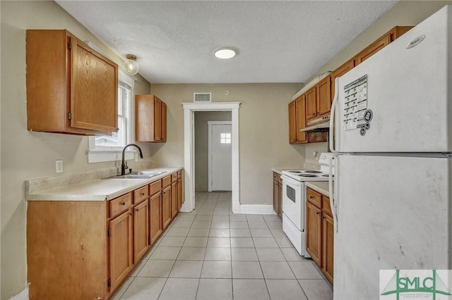 kitchen featuring white appliances, light tile patterned floors, light countertops, under cabinet range hood, and a sink