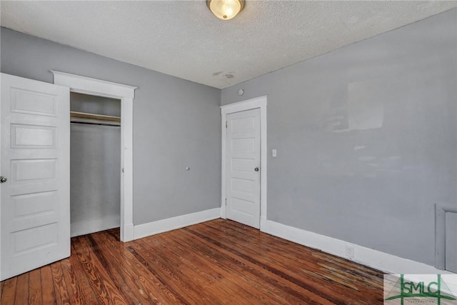 unfurnished bedroom featuring a textured ceiling, a closet, baseboards, and wood finished floors