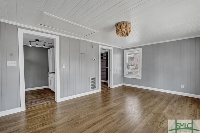 spare room featuring attic access, visible vents, wood finished floors, and ornamental molding