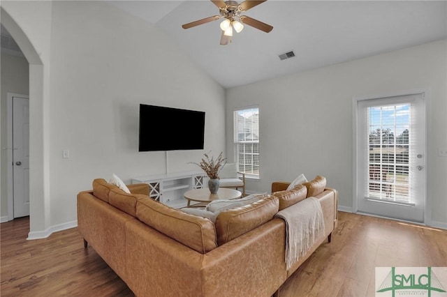 living area with lofted ceiling, ceiling fan, arched walkways, and wood finished floors