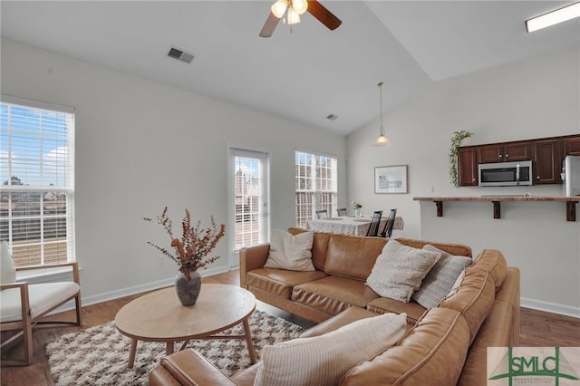 living room featuring a healthy amount of sunlight, visible vents, and wood finished floors