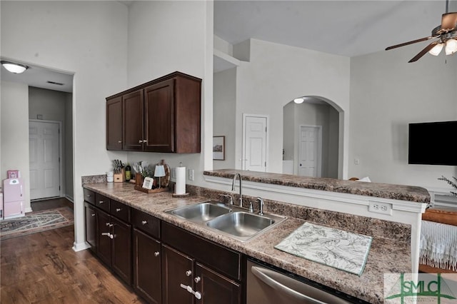 kitchen featuring arched walkways, dishwasher, dark wood-style flooring, dark brown cabinets, and a sink