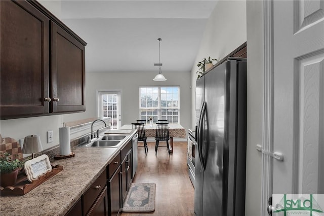 kitchen with stainless steel appliances, light wood-style floors, a sink, and dark brown cabinets