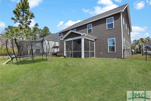 back of property with a yard, a sunroom, a trampoline, and fence