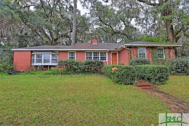 single story home with a front lawn, a chimney, and brick siding