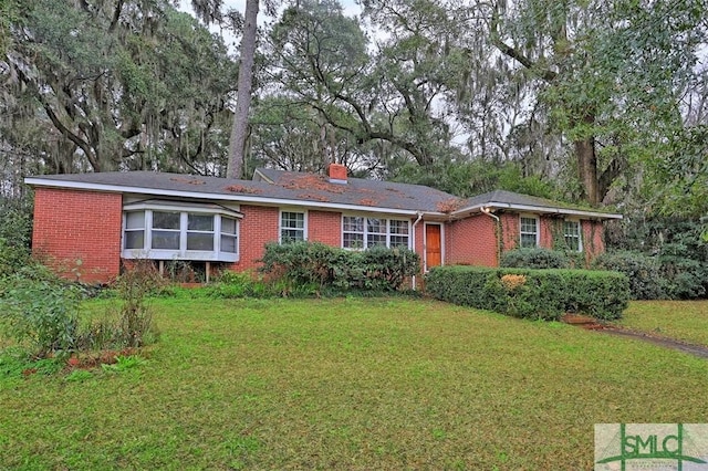 single story home with a chimney, a front lawn, and brick siding