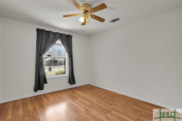 empty room featuring baseboards, visible vents, a ceiling fan, a textured ceiling, and light wood-type flooring