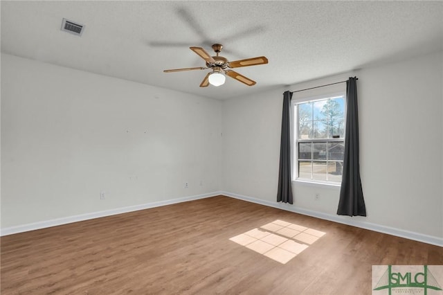 unfurnished room featuring baseboards, a textured ceiling, visible vents, and wood finished floors