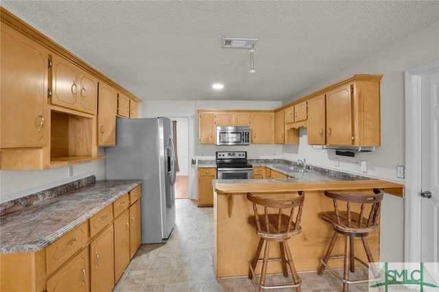 kitchen featuring visible vents, appliances with stainless steel finishes, a kitchen breakfast bar, a peninsula, and a sink