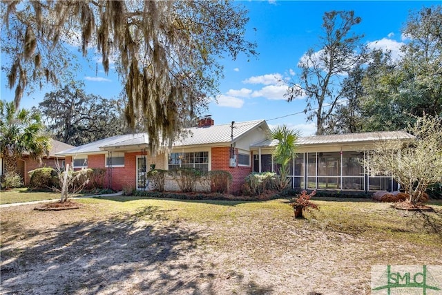 single story home with brick siding, a chimney, a front lawn, and a sunroom