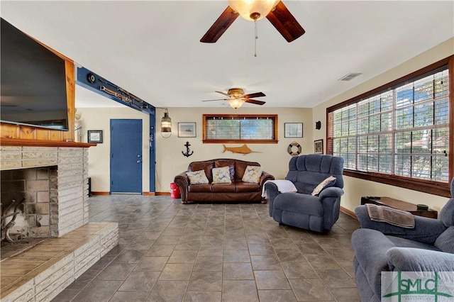 living area featuring visible vents, a fireplace, baseboards, and ceiling fan