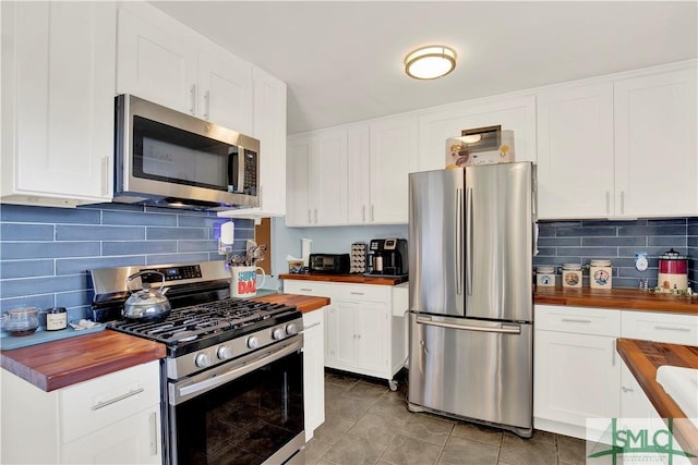 kitchen featuring stainless steel appliances, wood counters, and white cabinetry