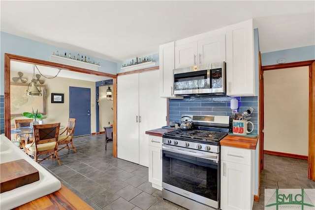 kitchen featuring stainless steel appliances, wooden counters, backsplash, white cabinetry, and baseboards